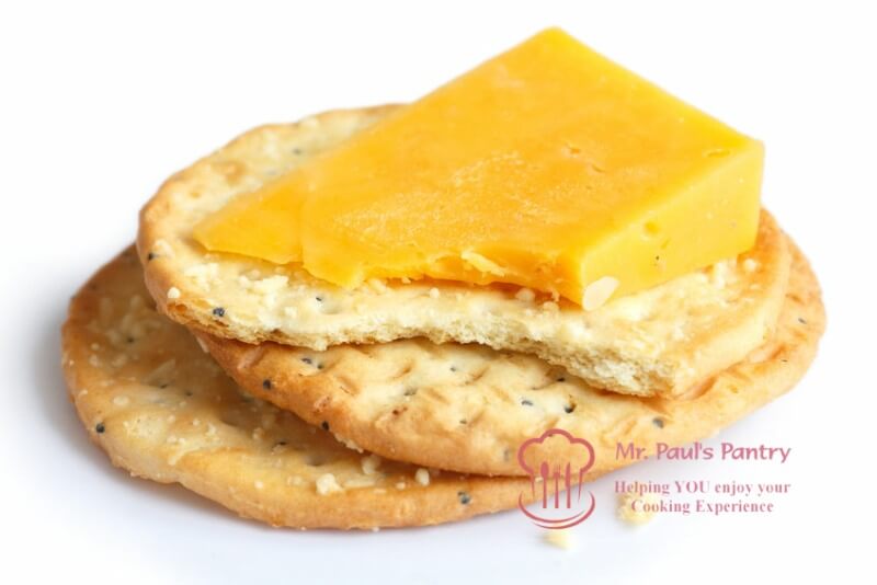 Three golden cheese crackers on white. With cheese.